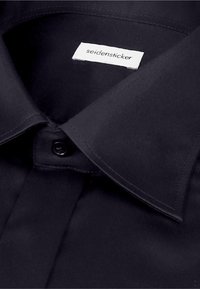 Chemise noire habillée avec un col pointu, boutonnée en haut, avec une étiquette blanche de la marque « seidensticker » à l'intérieur du col.