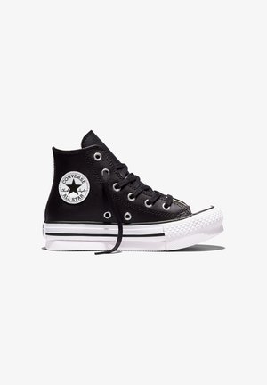 Zapatilla Converse Chuck Taylor All Star alta negra con suela de goma blanca y parche con el logotipo en el tobillo, vista lateral sobre fondo blanco.