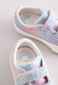 Glitzersneaker mit einem Farbverlauf von Rosa und Blau, ausgestattet mit Klettriemen und einem Regenbogenmuster auf der Innensohle. Weiße Sohlen.
