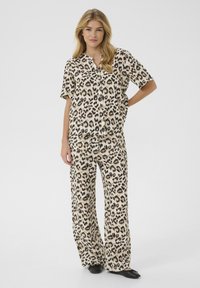 Leopard print loungewear set in beige and brown tones, featuring a short-sleeve button-up shirt and wide-leg pants made from soft fabric.