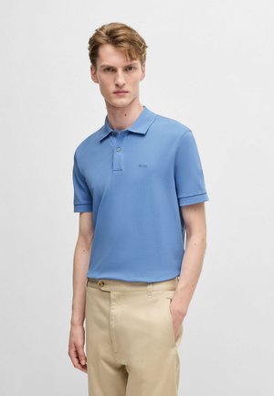 Polo shirt van lichtblauwe katoen, korte mouwen, kraag, klein logo op de borst. Gecombineerd met beige broeken met een knoopdetail.