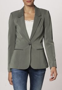 Khaki dopasowana marynarka z klapami, pojedynczym zapięciem na guzik i dwoma kieszeniami z przodu. Gładki materiał, dopasowany krój i elegancki design.