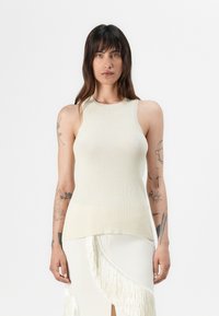 Bezrukávý ribbed pletený top v světle béžové barvě s kulatým výstřihem, se rovným střihem a texturovanou tkaninou.