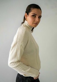 Witte gebreide coltrui met ribgebreide mouwen, kabelbreisel en een slim fit, gecombineerd met donkere jeans.