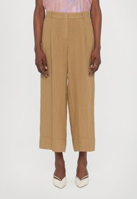 Brown wide-leg trousers with a textured finish, featuring a high waist and pleat detailing. Hem is folded for added dimension.