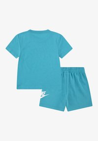 Tyrkysové bavlněné tričko s krátkým rukávem doplněné odpovídajícími šortkami. Na levé nohavici šortek se nachází bílé logo Nike.