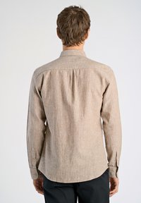 Camicia a maniche lunghe beige con righe verticali bianche, caratterizzata da un colletto a bottoni, una piega sul retro e polsini con bottone.