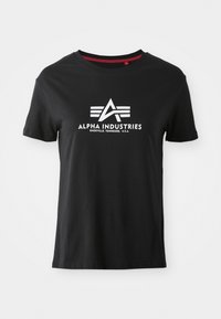 T-shirt en coton noir avec encolure ronde et manches courtes. Présente un logo blanc proéminent avec des lettres stylisées et des lignes d'accent à l'avant.