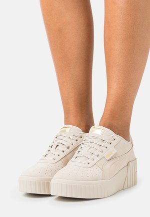 Beige plattform sneakers i mocka, med rund tå, snörningsdesign, sidologga och texturerad gummisula med vertikala spår.