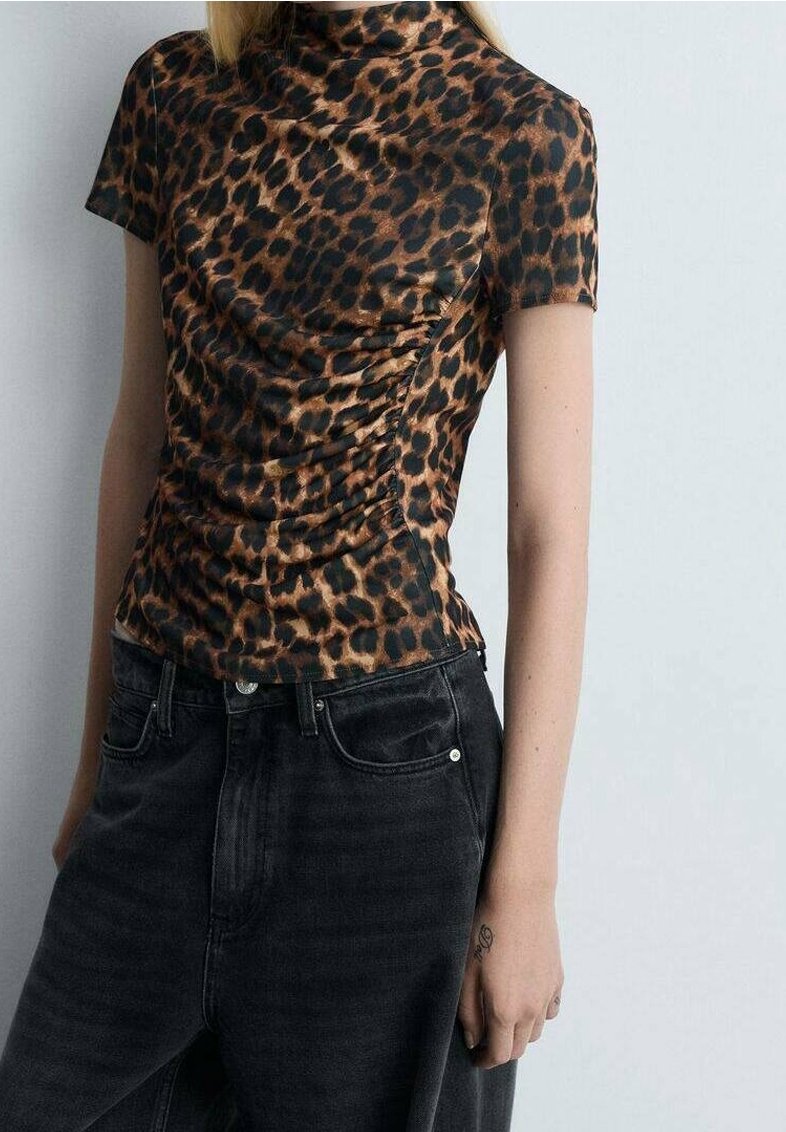 Top de leopardo con mangas cortas, cuello alto y textura arrugada. Combinado con vaqueros negros de cintura alta.