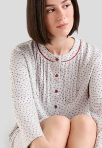 Camisa de noche gris con patrón floral, cuello redondo, tapeta de botones en la parte delantera y acentos rojos a lo largo del cuello y los botones.