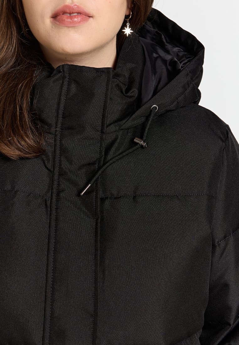 Veste matelassée noire avec un col haut, un cordon de serrage ajustable et une doublure intérieure lisse. Comprend des sections matelassées et du matériel métallique.
