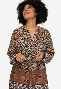 Robe à imprimé léopard avec un décolleté en V, des manches longues et une taille à nouer. Comporte un tissu marron orné de cœurs et d'étoiles orange près de l'ourlet.