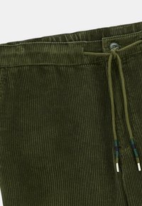 Pantalons en velours côtelé vert olive avec une ceinture élastique, un bouton et un lien à tirage avec des accentuations turquoise et violet.