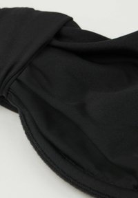 Czarna tkaninowa opaska na oczy o gładkiej fakturze, z zakręconym wzorem i elastycznym paskiem zapewniającym pewne dopasowanie. Miękki, lekki materiał.