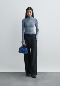 Knitted blue and white striped turtleneck, black wide-leg trousers, and blue patterned handbag; smooth texture and fitted design.