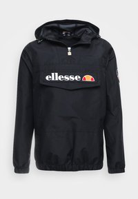 Mustapukuinen tuulitakki hupulla, jossa on etuvetoketju ja suuri tasku. "ellesse"-logo näkyvästi esillä. Elastiset hihansuut ja helma.