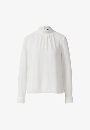 Blouse blanche à manches longues avec col haut, col et poignets plissés, et une petite ouverture en forme de clé à l'avant.