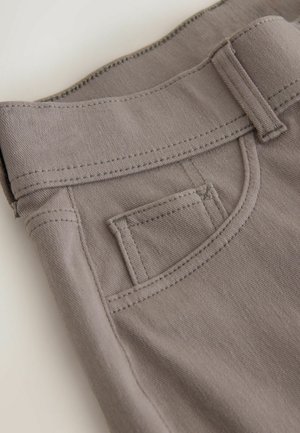 Light grey cotton pants with a flat waistband, curved front pocket, and double-stitched seams. Fabric is smooth and textured.