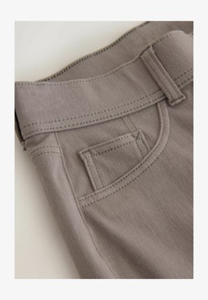 Hellgraue Baumwollhose mit flachem Bund, geschwungenen Fronttaschen und doppelt genähten Nähten. Der Stoff ist glatt und strukturiert.