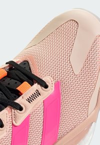 Športové tenisky s vrchnou časťou z jemnej ružovej sieťoviny, čierno-oranžovými šnúrkami, plastovými akcentmi a textúrovanou gumovou podrážkou.