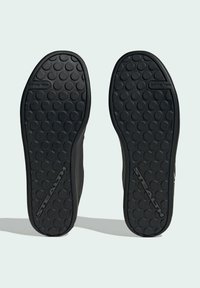 Sole in gomma nera con motivo circolare antiscivolo e bordi testurizzati. Presenta la parola "STEALTH" impressa vicino al tallone.