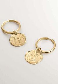 Llavero en tono dorado con dos medallas circulares grabadas, una con la letra "W" y la otra con la "S". Acabado metálico suave y acentos decorativos.
