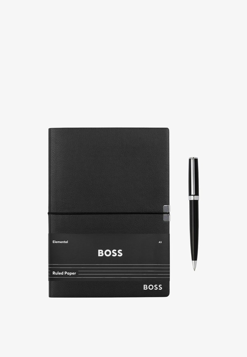Carnet A5 noir à lignes, étiqueté "BOSS", avec un stylo noir orné d'accents argentés posé à côté sur un fond blanc.
