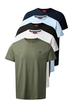 Mann mit kurzen dunklen Haaren und Bart, trägt hellblaues kurzärmeliges T-Shirt und dunkle Hose, steht vor schlichtem hellem Hintergrund.