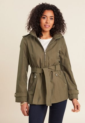 Giacca verde oliva con cintura e cappuccio. Presenta tasche con zip, chiusura frontale con zip e polsini con bottone. Realizzata in tessuto liscio e resistente.