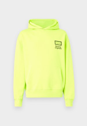 Neon rumena kapuca s sprednjim žepom, nastavljivim vrvico za kapuco in majhnim grafičnim motivom na levem prsnem delu. Bombažni material z rebrastimi manšeti.