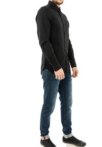 Camisa negra de manga larga con botones, diseño ajustado, combinada con pantalones vaqueros azules y zapatillas negras con suela texturizada y acentos rojos.