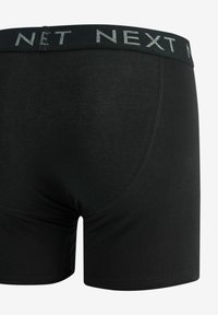 Schwarze Baumwoll-Boxershorts im Slim-Fit-Design, mit einem weichen Bund, der mit dem grauen "NEXT"-Logo versehen ist. Sanfte Textur und minimale Nähte.