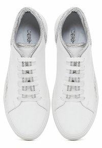 Weiße Ledersneaker mit glatter Textur, flachen Schnürsenkeln und silbernen Akzenten entlang des Kragens und der Schnürsenkelbereich. Minimalistisches Design.