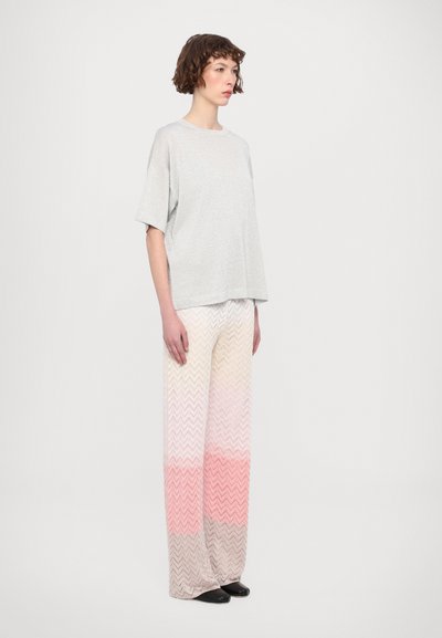 Gray short-sleeve top with a relaxed fit, paired with wide, chevron-patterned pants in a gradient of pastel colors, ending in pink.