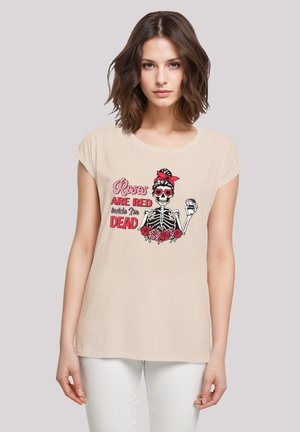 Beige T-Shirt mit kurzen, umgeschlagenen Ärmeln. Verziert mit einem bunten Grafikmotiv eines Skeletts mit Rosen, das rote Sonnenbrillen trägt und ein Getränk in der Hand hält.
