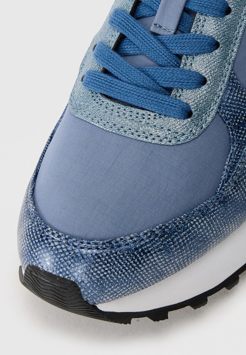 Blauwe sneaker met een mix van textuurmaterialen, waaronder gladde en glanzende stof, met ronde veters en een rubberen zool.