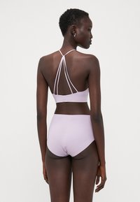 Bralette violet clair avec un design de bretelles croisées à l'arrière, associé à un bas taille haute assorti, texture lisse, coutures minimales.