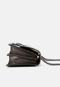 Sort håndtaske formet som en åben bog, tekstureret overflade, sølvkæde som rem og dekorative beslag på toppen.