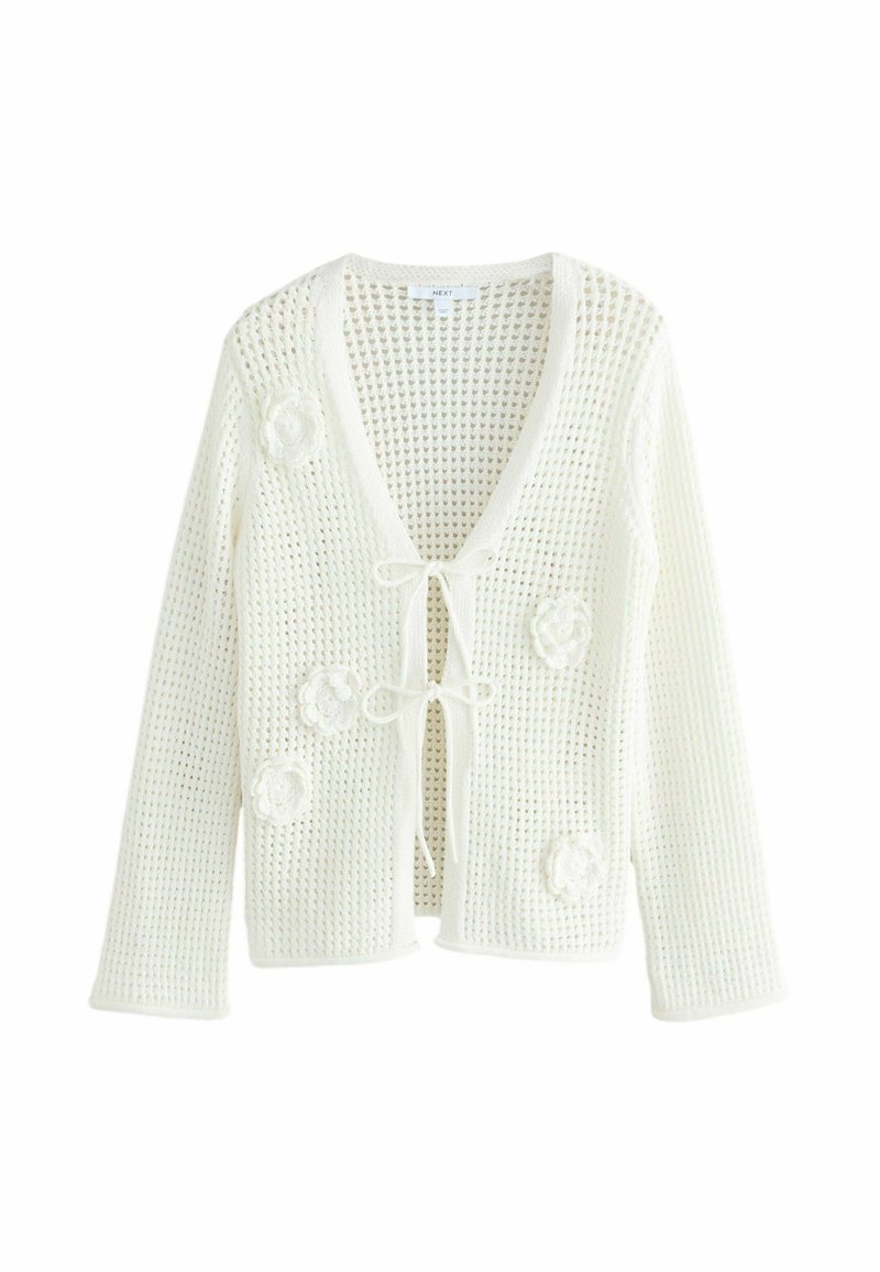 Cardigan bianco all'uncinetto con scollatura a V, maniche lunghe e chiusura con laccetto. Presenta applicazioni floreali e un motivo a maglia aperta per un aspetto testurizzato.