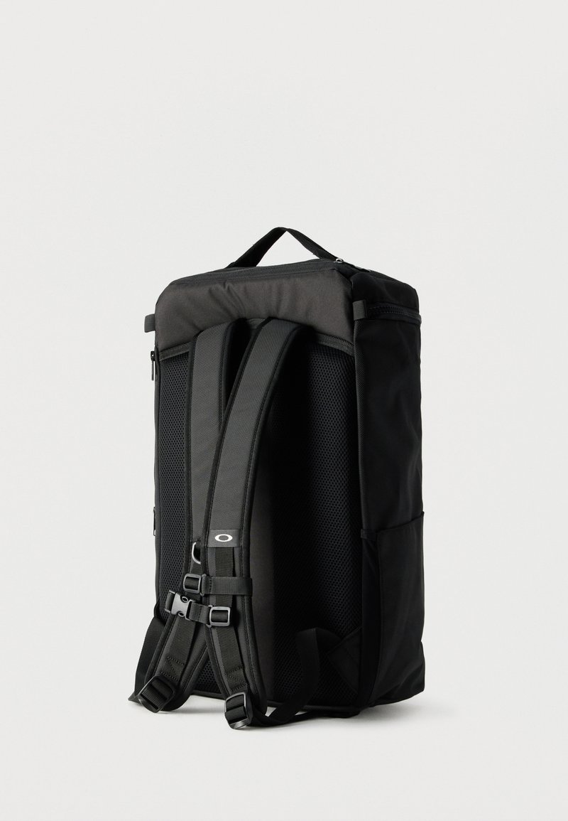 Sac à dos rectangulaire noir avec bretelles rembourrées, boucle pectorale, panneau arrière en mesh et poignée supérieure sur fond blanc.