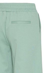 Lichtgroene sweatpants met een elastische tailleband, voorzien van een zijzak en een platte achterzak. Zachte, gemêleerde stof.
