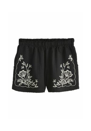 Musta shortsit, joissa valkoiset kukkaompeleet sivuilla, joustava vyötärönauha ja teksturoitu kangas löysällä istuvuudella.