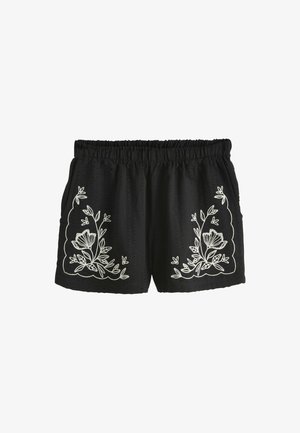 Shorts noirs avec broderie florale blanche sur les côtés, taille élastique et tissu texturé avec une coupe ample.