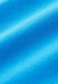 Texturiertes blaues Gewebe mit einer glatten, leicht glänzenden Oberfläche. Die Farben wechseln von hellblau zu dunkelblau und zeigen ein feines Rippenmuster.