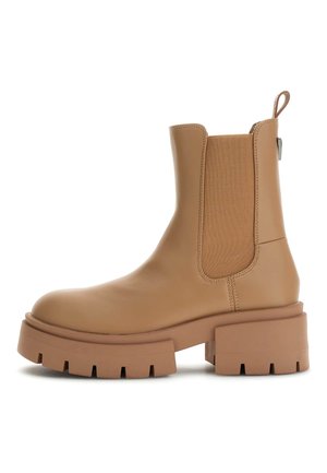Botte de cheville en cuir tan avec des panneaux élastiques sur les côtés, semelle épaisse et tirette au talon. Texture lisse et construction solide.