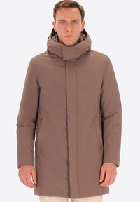 Cappotto leggero marrone con colletto alto e zip nascosta. Presenta due tasche laterali e un design elegante e aerodinamico. Texture liscia.