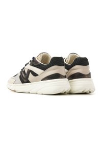 Sneaker mit einem beigen und schwarzen Design, aus Textil und Leder, mit einer strukturierten Oberfläche und einer leichten weißen Sohle.