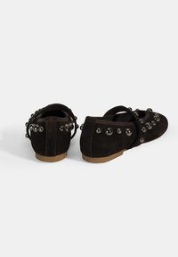 Braune Wildleder-Ballerinas mit runden Zehen, Knöchelriemen und dekorativen silberfarbenen Nieten entlang der Seiten und hinten.