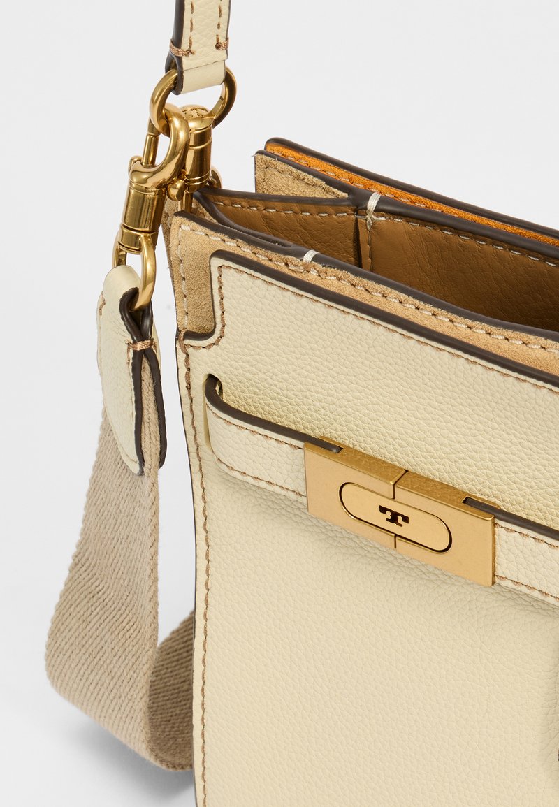 Hellbeige Leder-Crossbody-Tasche mit strukturiertem Finish, goldener Verschluss und kontrastierenden braunen Akzenten. Beinhaltet einen stabilen, verstellbaren Riemen.